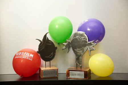 Die Preise EMO und EMMI mit lächelnden Gesichtern und Luftballons im Hintergrund, Foto: Kinderfilmtage