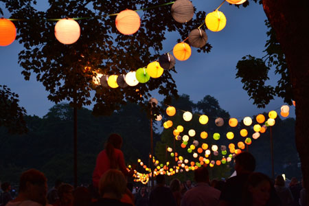 Verschiedenfarbige Lampions vor dunklem Himmel im Westfalenpark, im unteren Bildteil sind viele Menschen, ein Kind wird Huckepack getragen Foto: Stefanie Kleemann